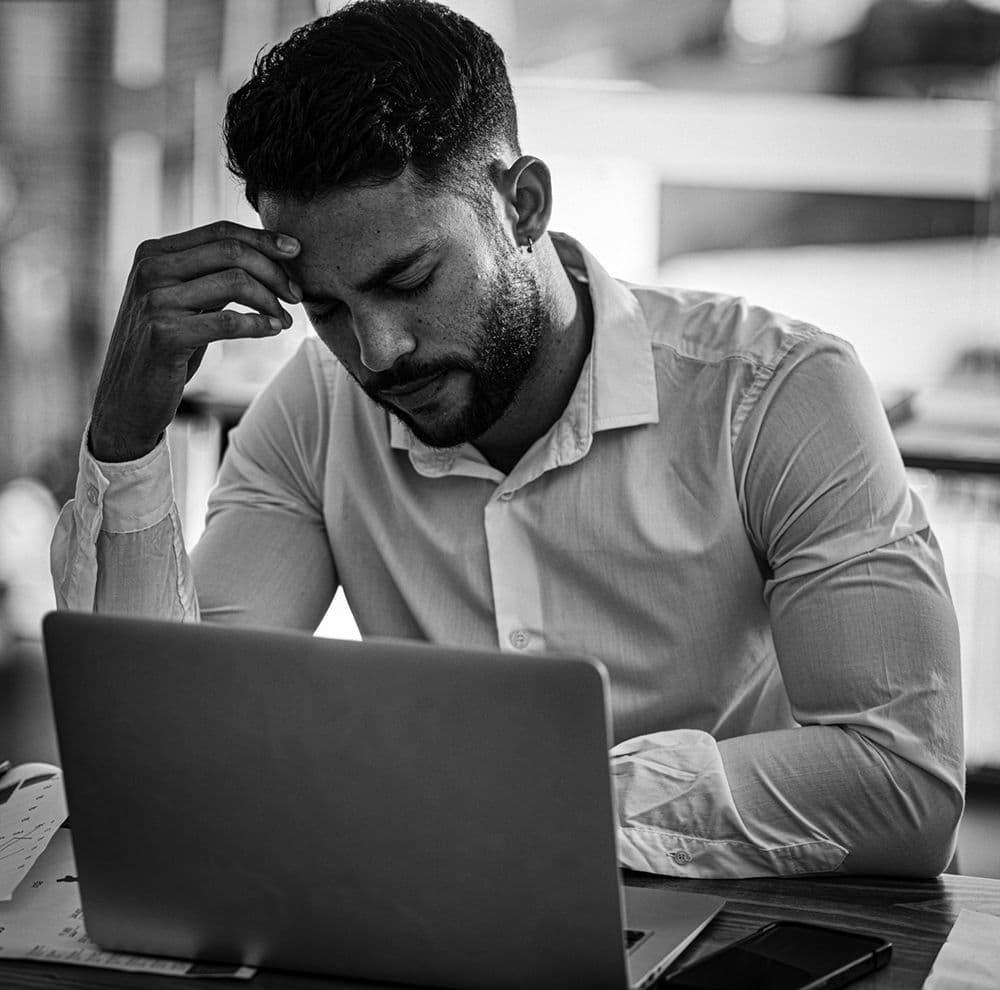 A person thinking while working on a laptop